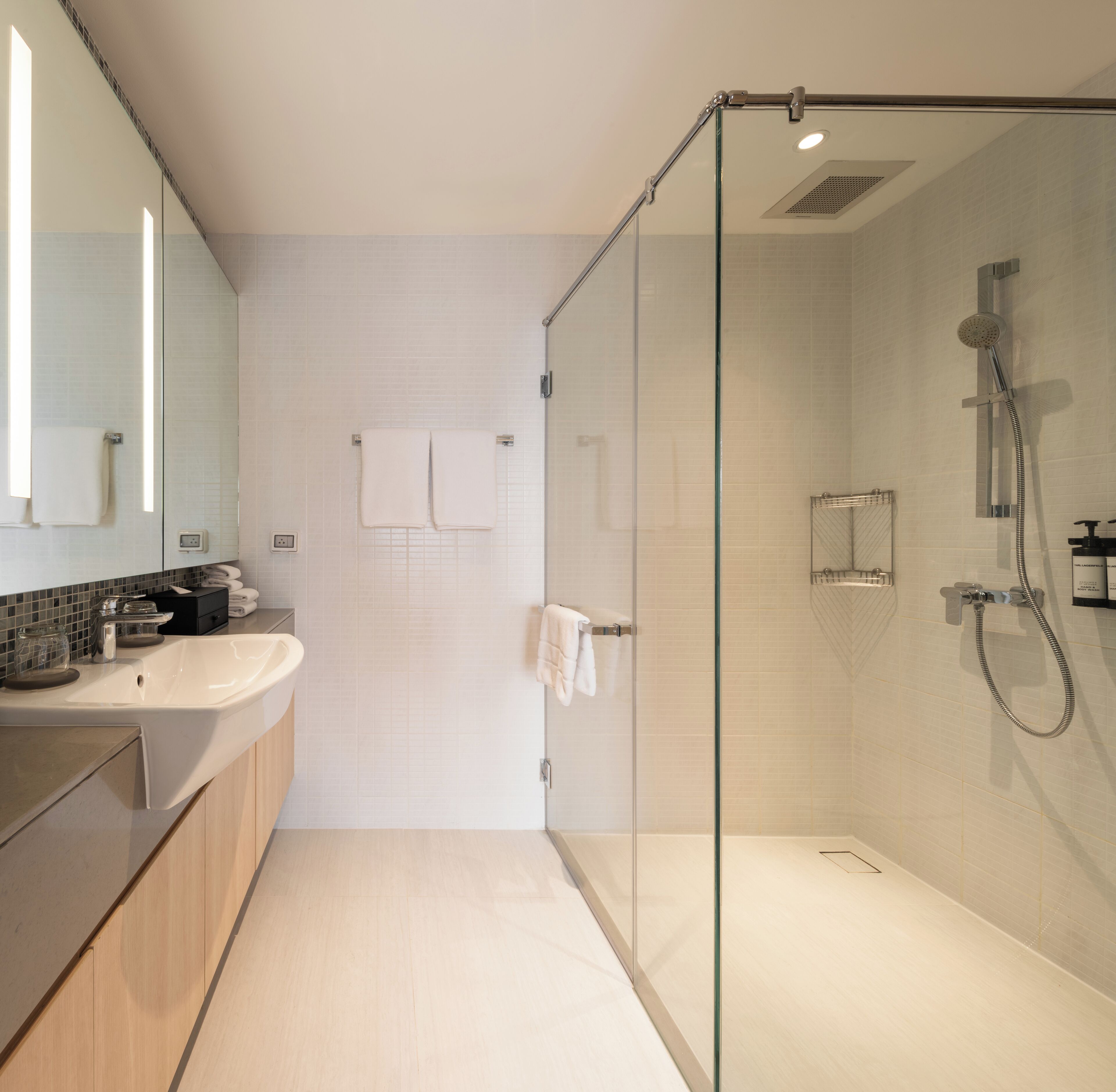 A modern bathroom with a glass-enclosed shower, a sink, and a mirror.