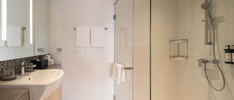 A modern bathroom with a glass-enclosed shower, a sink, and a mirror.