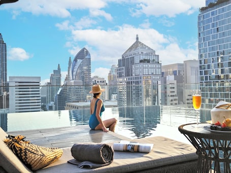 Una piscina al aire libre, sombrillas, sillones reclinables de piscina