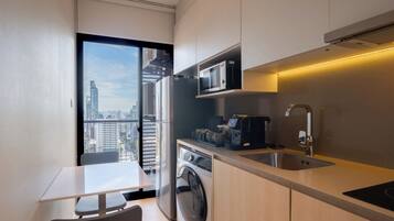 A modern kitchen with a washing machine, microwave, and coffee maker.