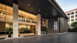 Una entrada de hotel moderna con un mostrador de recepción, ventanas amplias y un letrero que dice "Sindhorn midtown".