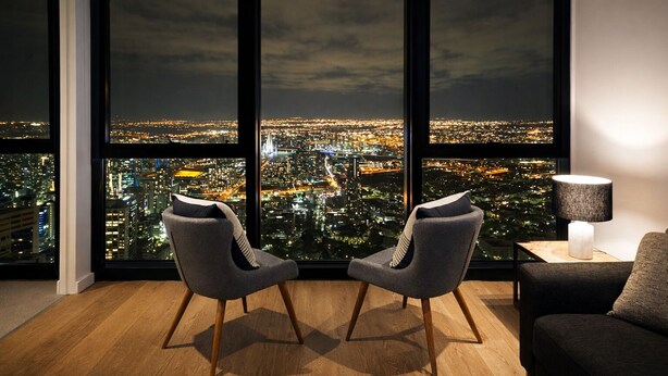 Una sala de estar moderna con un amplio ventanal que ofrece vistas nocturnas de la ciudad.