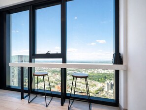 Une pièce moderne avec de grandes fenêtres, deux tabourets et une table blanche.