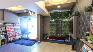 A reception area with a live max pharmacy, a reception desk, a seating area, and a wall with greenery. - Hotel Livemax Shinjuku East (Tokyo)