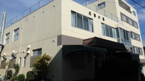 Un edificio de varios pisos con fachada color beige, ventanas amplias y una entrada visible con toldo verde.