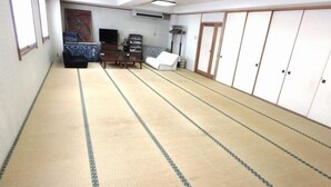 Una habitación con tatami, sofá, televisor y armarios de almacenamiento.