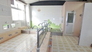 Baño público con varios lavamanos, un secador de manos y un inodoro.