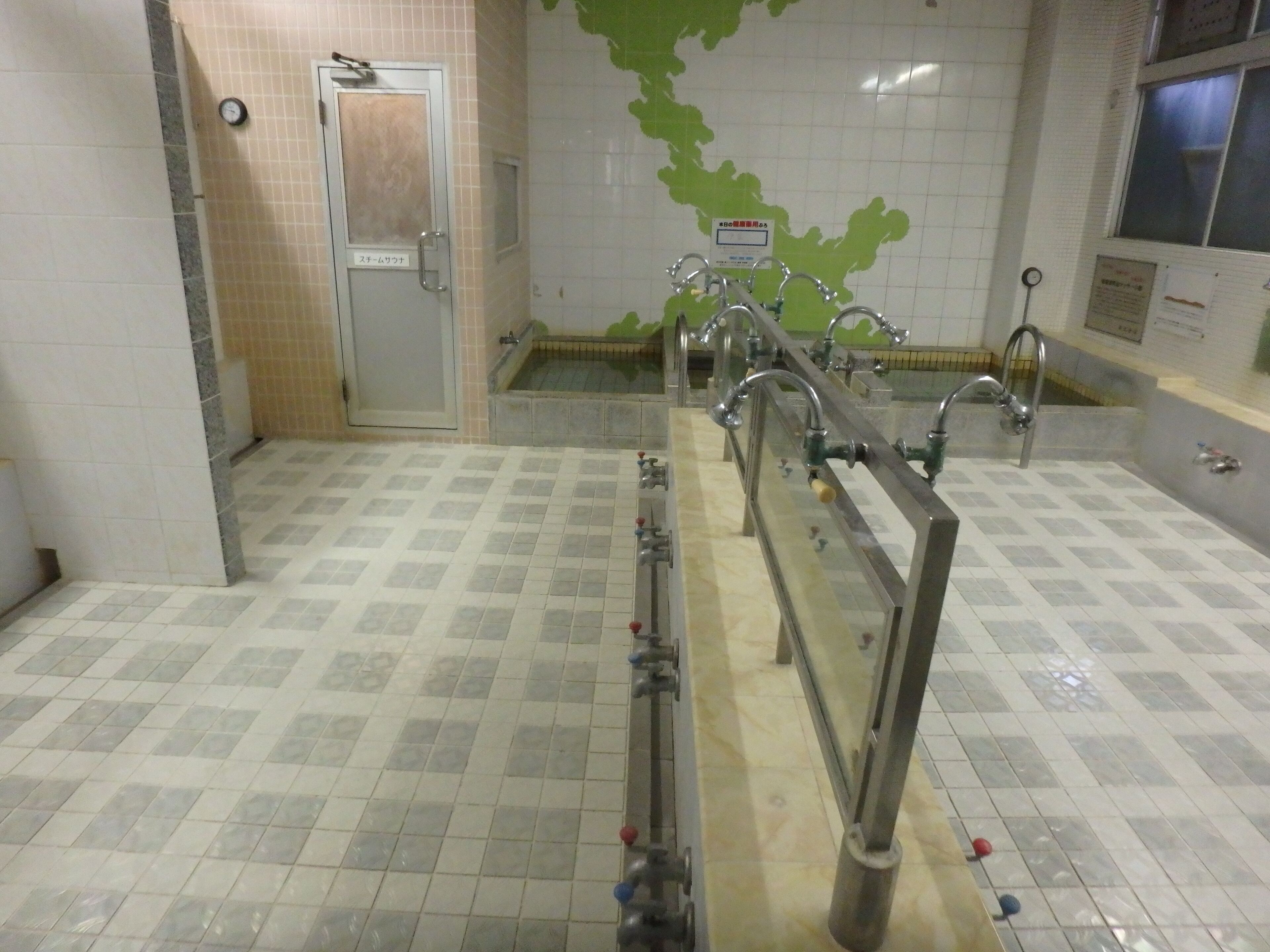 A public restroom with multiple sinks, a clock, and a tiled floor.