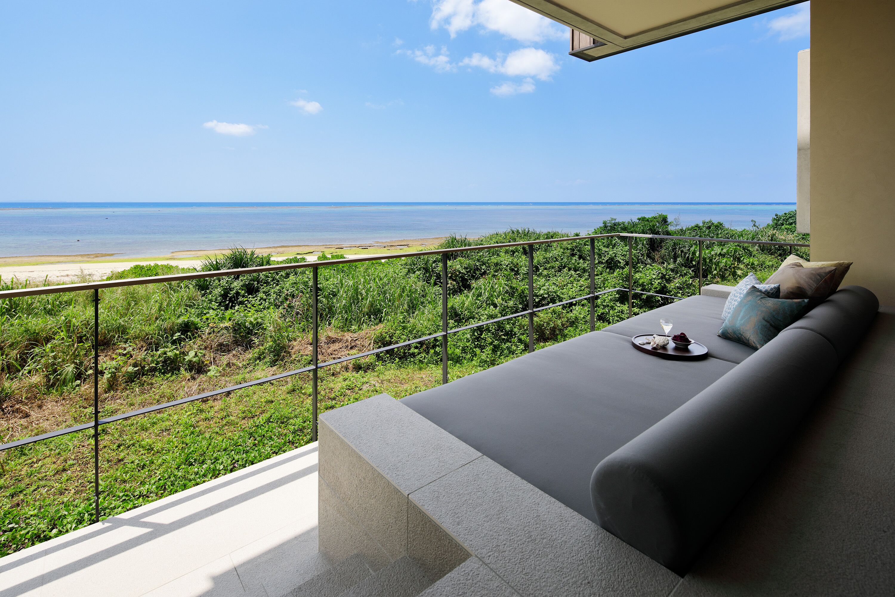 A balcony with a view of the beach and ocean.