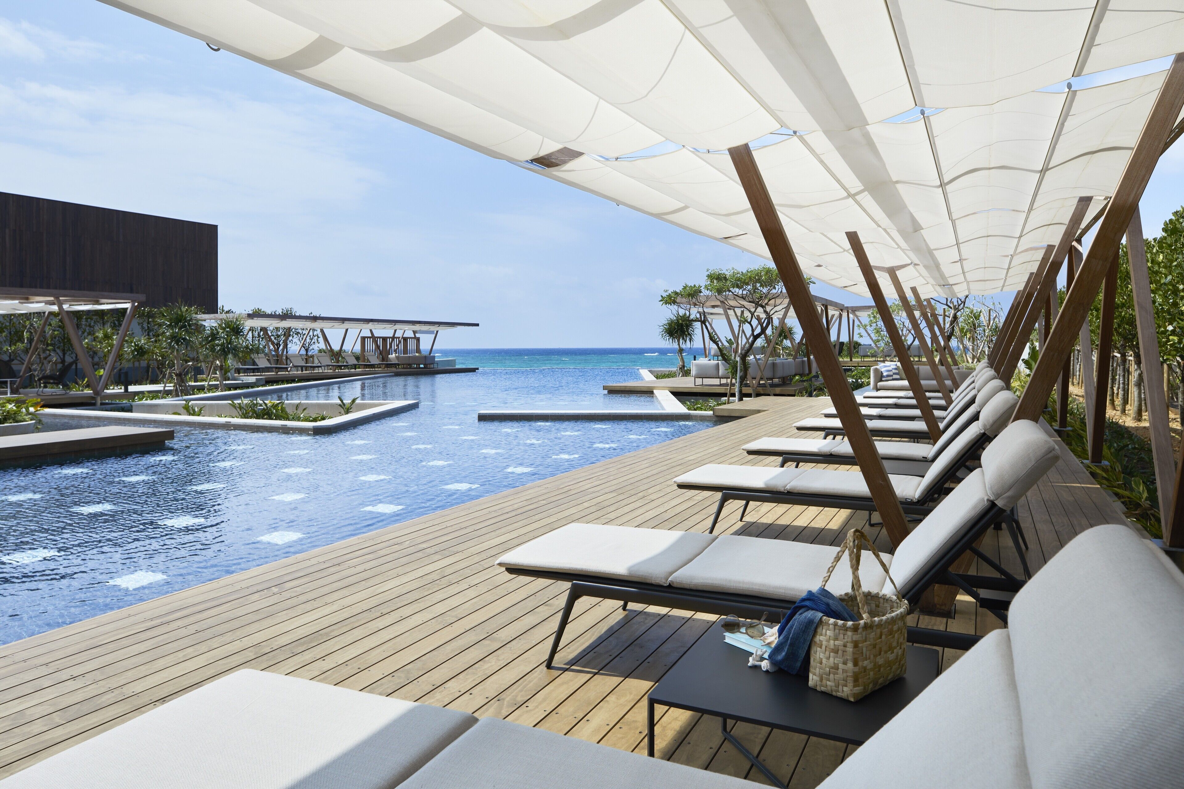 A poolside area with lounge chairs and a view of the ocean.