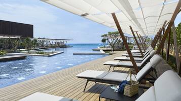 A poolside area with lounge chairs and a view of the ocean.