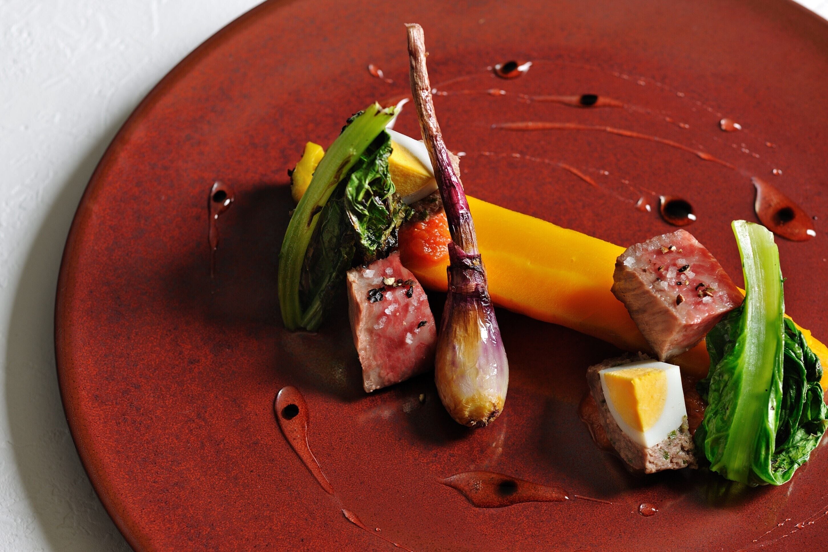 A plate of food with various ingredients including meat, vegetables, and a sauce.