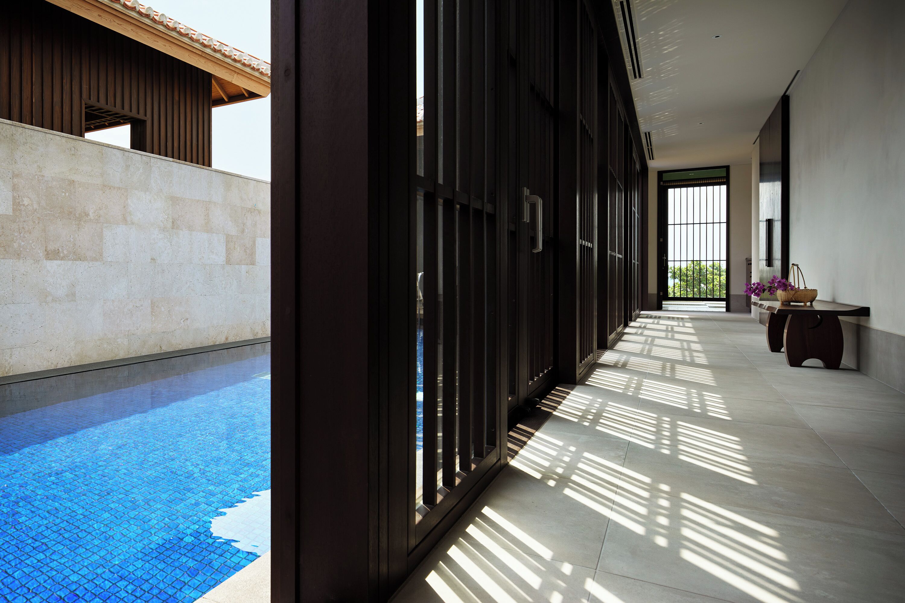 Un interno moderno con piscina, un corridoio con una panca e vista sull'esterno.