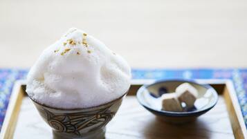 Un bol de glace pilée décorée d’un motif, posé sur un plateau sur lequel est disposée une nappe bleue à motifs.