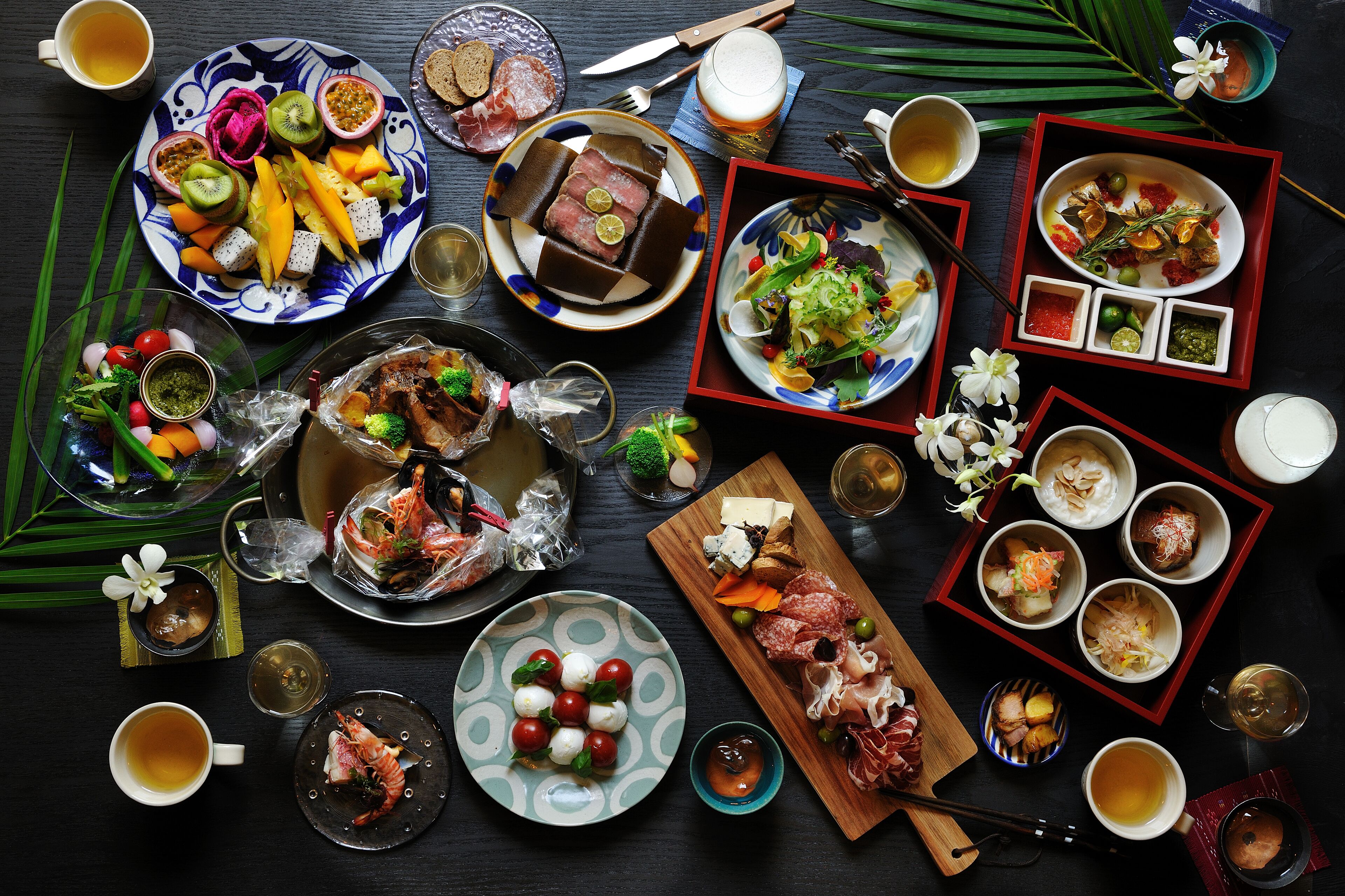 Una variedad de platos y bebidas sobre una mesa, incluyendo sushi, sashimi y un tazón de sopa.