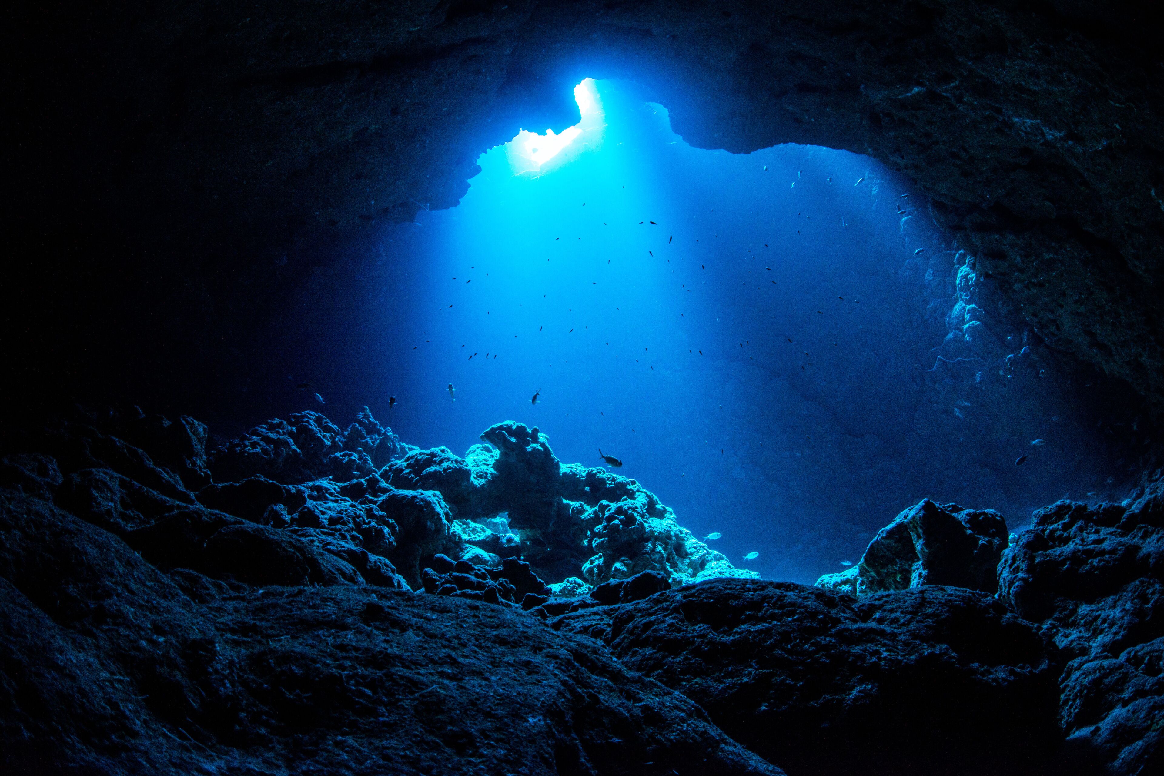 An underwater cave with a central opening allowing light to penetrate.