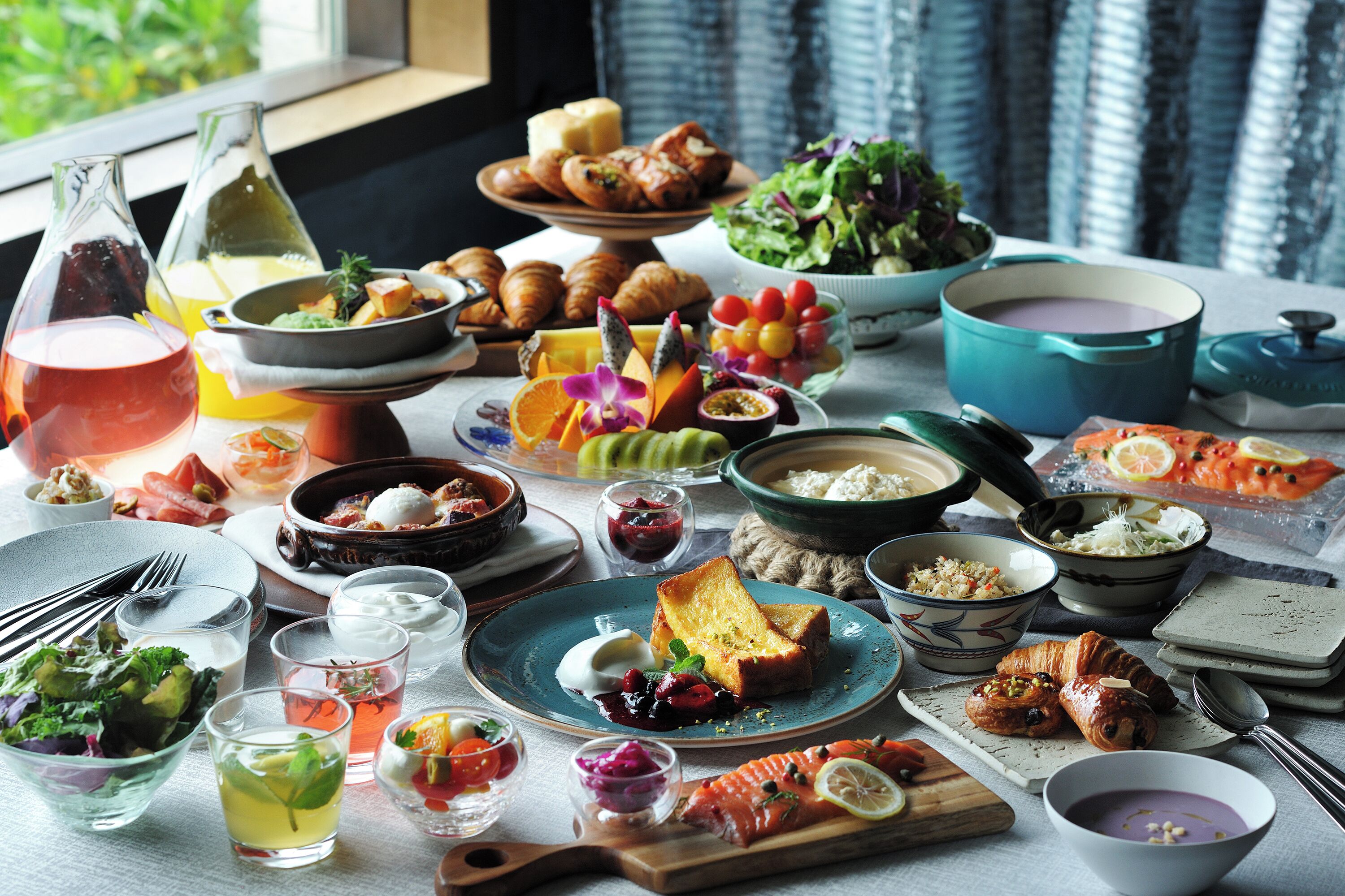 A table set with various dishes, drinks, and a teapot.