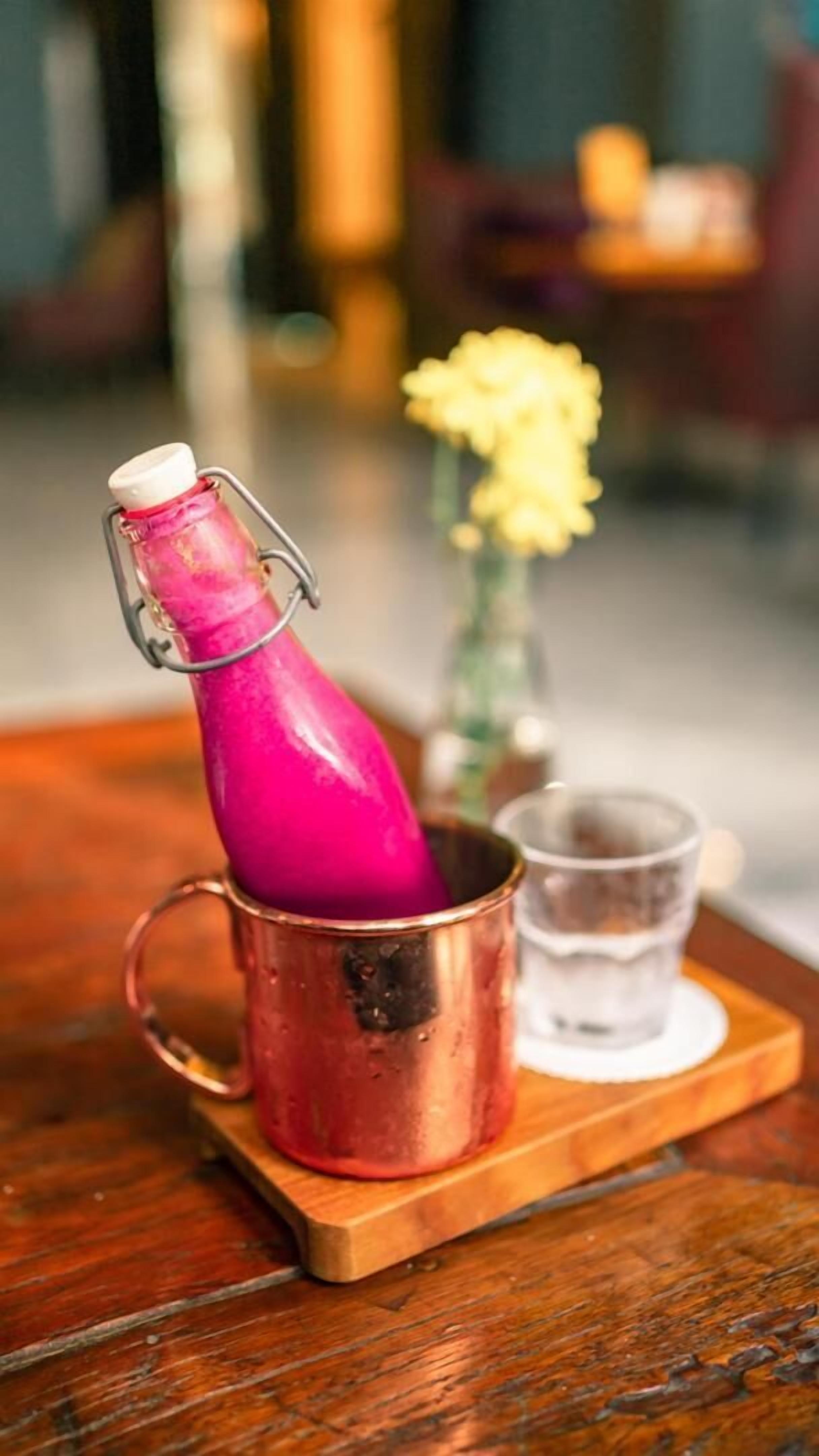 A copper bottle with a cork stopper on a wooden tray.
