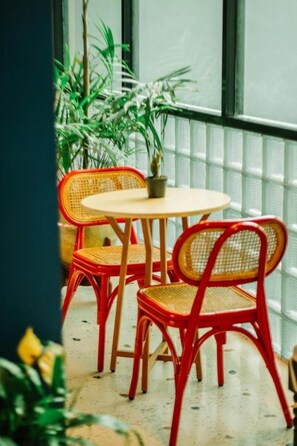 A small round table with two red chairs and a potted plant.