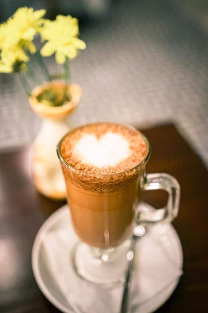 A clear glass mug with a handle, filled with a dark liquid, possibly coffee, on a saucer.