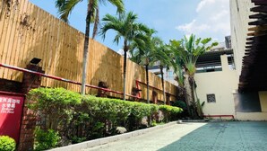 A courtyard with a wooden fence, palm trees, and a paved walkway. - Wen Mei Motel (Nantou)