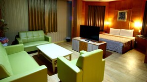 A hotel room with a green sofa, a bed with white linens, a TV, and a small table. - Wen Mei Motel (Nantou)