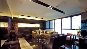 A modern living room with a sofa, armchairs, a coffee table, and a TV. - Casa (Kowloon)
