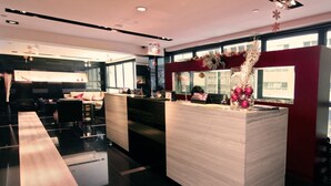 A modern hotel lobby with a reception desk, seating area, and large windows. - Casa (Kowloon)