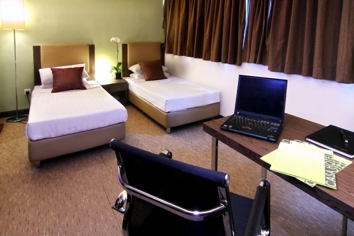 A hotel room with two beds, a desk with a laptop, and a chair.