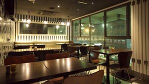 A restaurant with a modern interior, featuring a mix of wooden and metal furniture, large windows, and a striped wall design. - Casa (Kowloon)