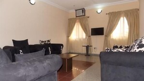 Ein Wohnzimmer mit zwei Sofas, einem kleinen Tisch und einem an der Wand befestigten Fernseher.