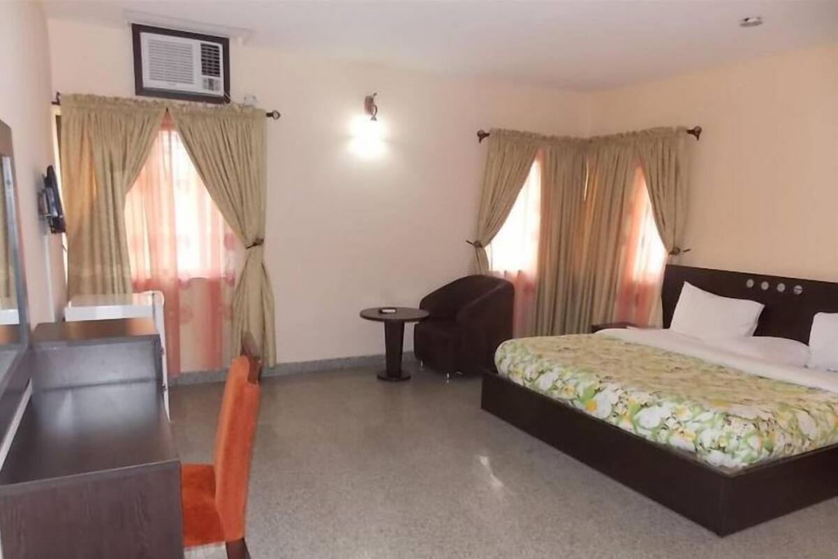 Une chambre d’hôtel avec un lit, un bureau, une chaise et une petite table.