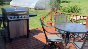 Una terraza de madera con una parrilla, una mesa y sillas.