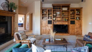 A spacious living room with a fireplace, wooden shelving, and comfortable seating.
