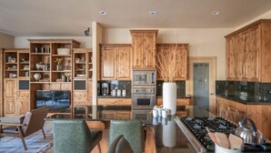 A modern kitchen with wooden cabinets, a central island with a stove, and built-in appliances.