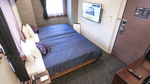 A hotel room with a bed, a desk, a chair, a window with curtains, a wall-mounted TV, and a door with a lock. - Hotel Live Max Tokyo Kanda Station (Tokyo)