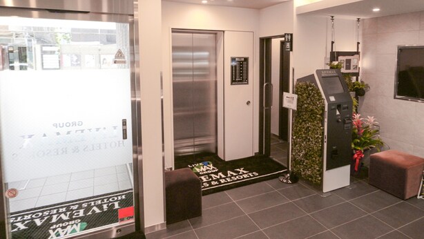 A modern elevator with a digital display, a reception area with a digital screen, and a sign for Max Resorts. - Hotel Live Max Tokyo Kanda Station (Tokyo)