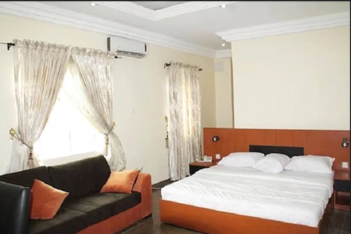 Una habitación de hotel con cama, sofá y cortinas.