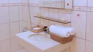 A bathroom with a sink, a mirror, a shower, and a shelf with toiletries. - Cheng Lan Hotel (Yuchi)