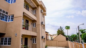 A multi-story building with balconies, air conditioning units, and a gated entrance. - Tennys Place Apartments GARKI (Abuja)
