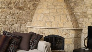 A stone fireplace with a mantel, a sofa with patterned cushions, and a clock on the mantel.