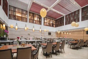 A spacious dining area with multiple tables and chairs, large windows, and hanging spherical light fixtures. - Auden  International  Hotel (Shenzhen)