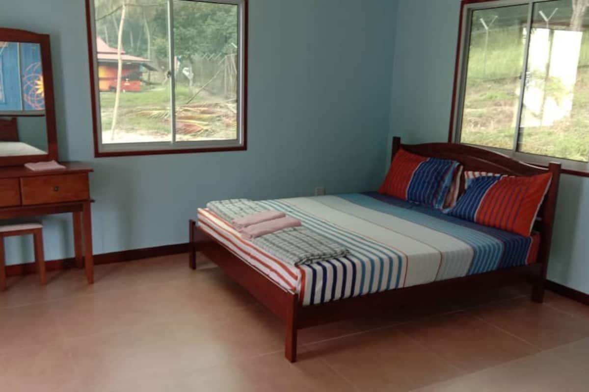Un dormitorio con cama, cómoda y ventana.
