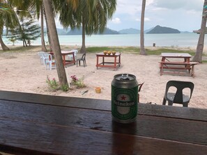 A beachside table with a Heineken can, chairs, and a table with fruits. - Wild Pasir Panjang Villas (Pulau Tuba)