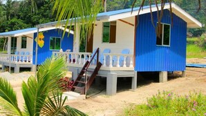 Deux cabines bleues et blanches dotées d’un balcon, entourées de verdure.