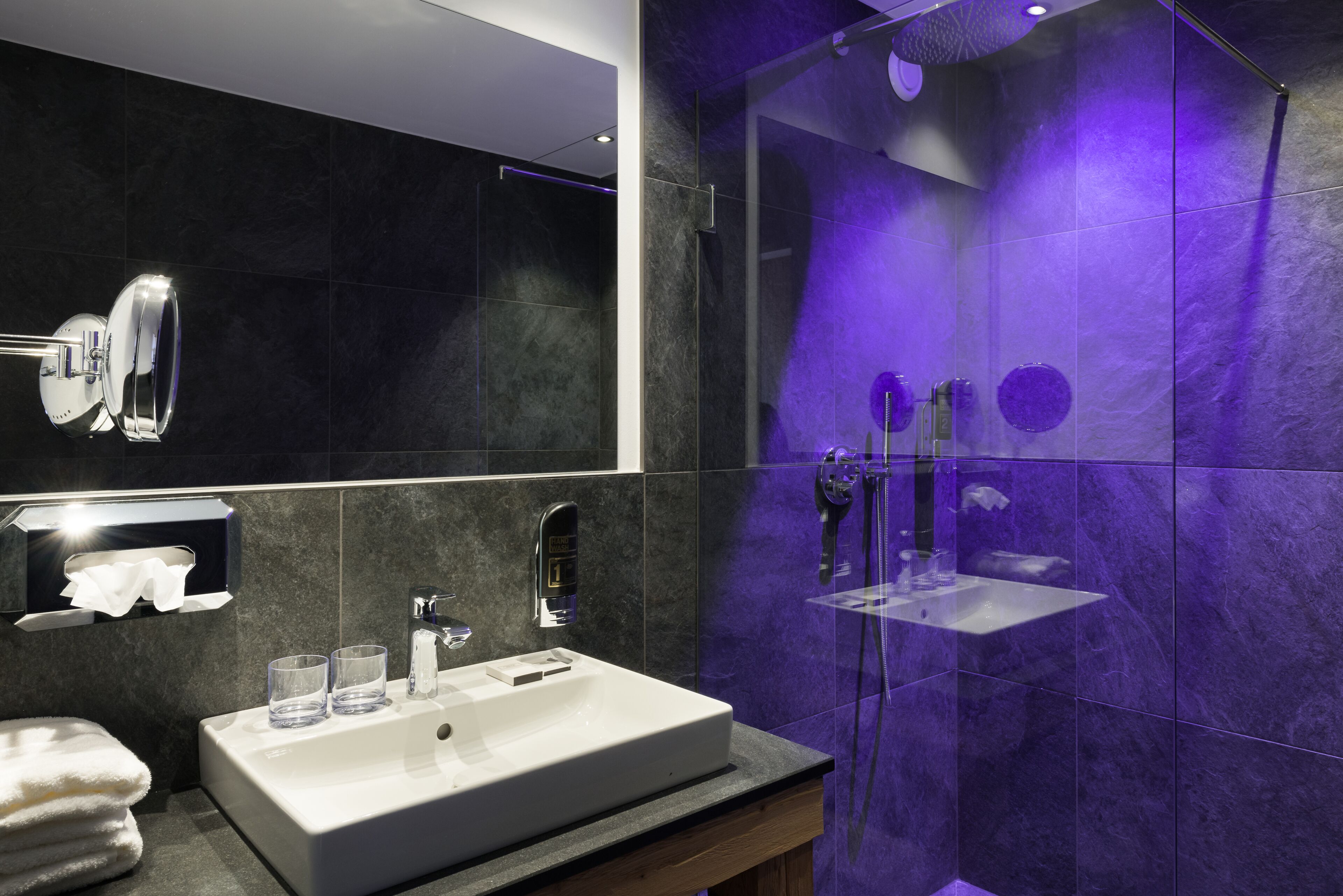 Un baño moderno con un lavamanos grande, un espejo y un box de ducha de vidrio.