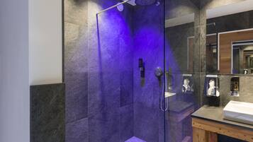 Un baño moderno con ducha envuelta en vidrio, tocador de madera y un espejo grande.