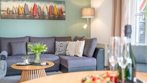 A modern living room with a grey sofa, a wooden coffee table, and a painting of sailboats on the wall. - Miss Loddin, Karl's Apartment (includes beach chair) - + Miss Loddin, Karl (Loddin)