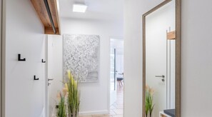 A hallway with a modern door, a large abstract wall art piece, and a mirror with a decorative frame.