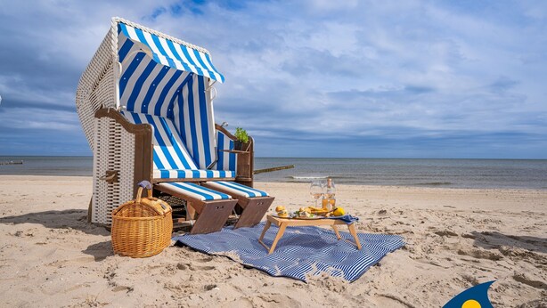 A beachside lounge with striped awnings, lounge chairs, a wicker basket, and a table with drinks and fruits. - Miss Loddin, Karl's Apartment (includes beach chair) - + Miss Loddin, Karl (Loddin)